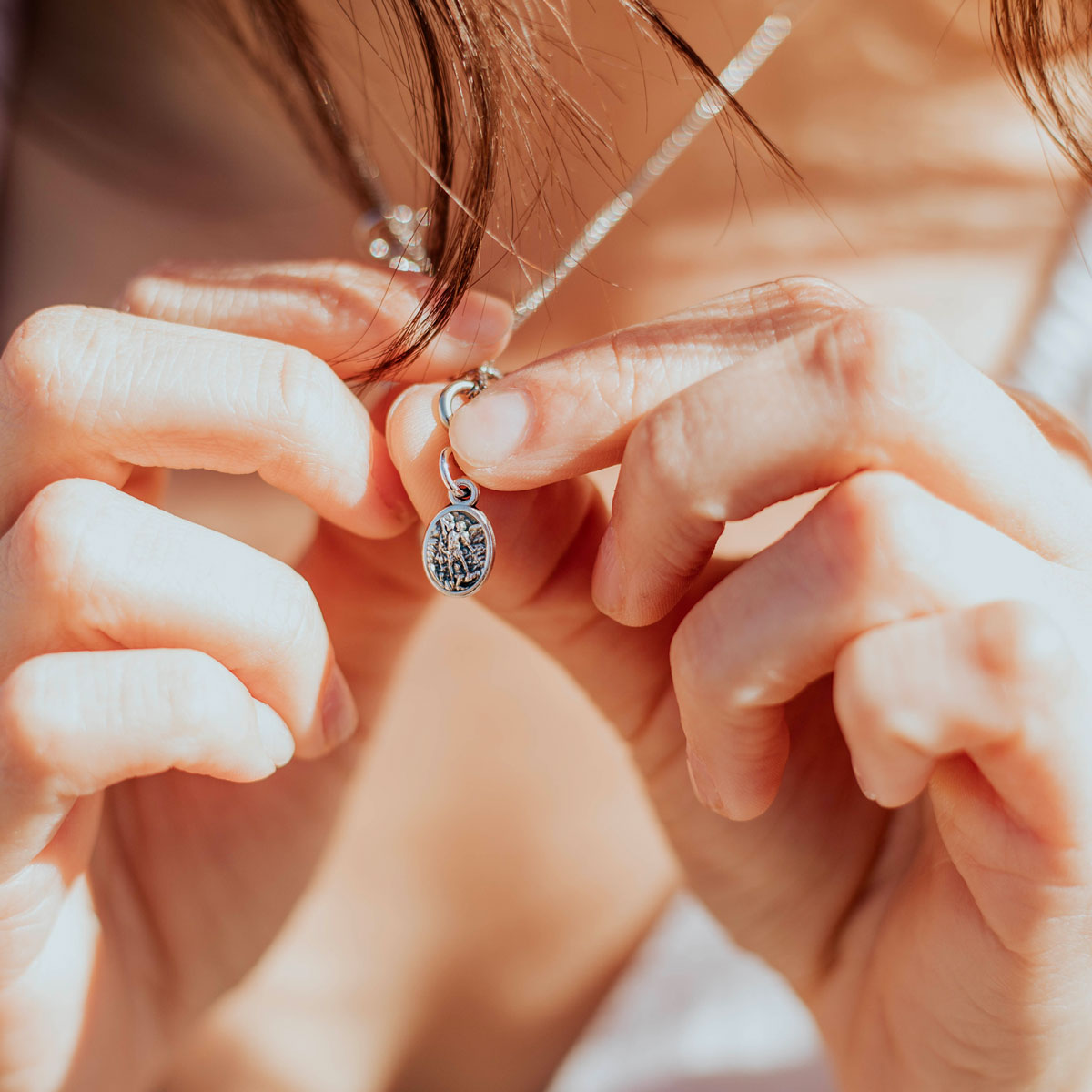 close up of petite oval archangel michael silver tone medal worn on necklace chain