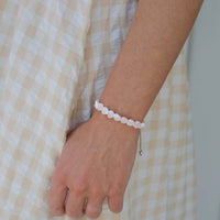 Person wearing a pink and white heart beaded bracelet on a checkered fabric background