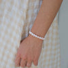 Person wearing a pink and white heart beaded bracelet on a checkered fabric background