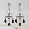 Pair of silver earrings with black teardrop beads on a light background