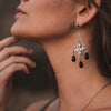 Close-up of a woman wearing Deep Faith  dangling earring with black crystals.