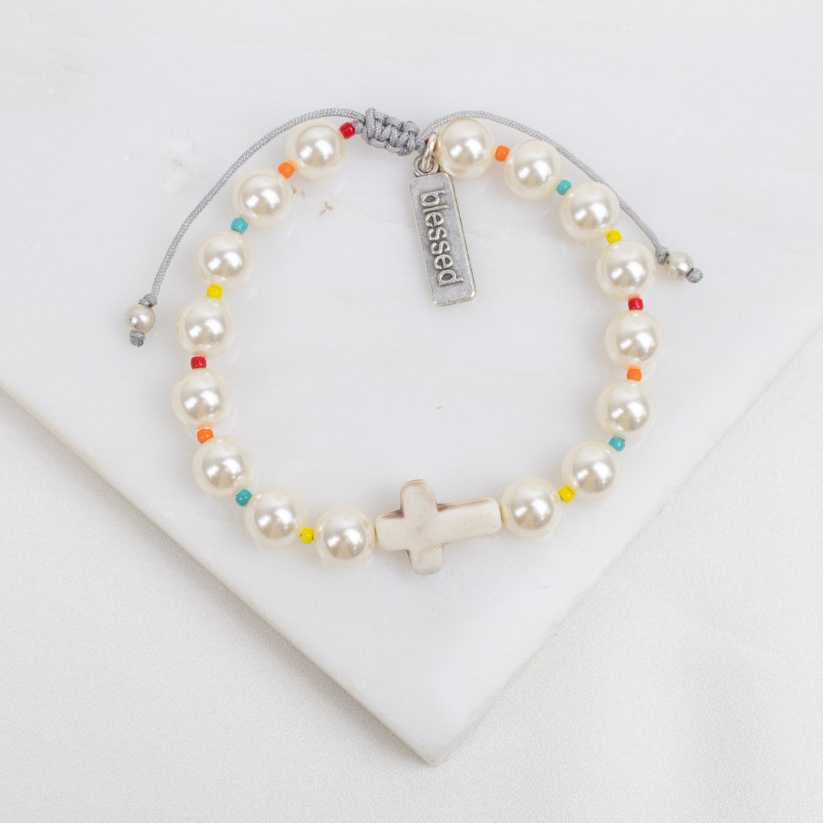 Pearl bracelet with colorful beads and 'blessed' tag on a white background