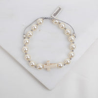 Pearl bracelet with a cross charm on a white background