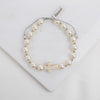 Pearl bracelet with a cross charm on a white background