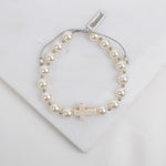 Pearl bracelet with a cross charm on a white background