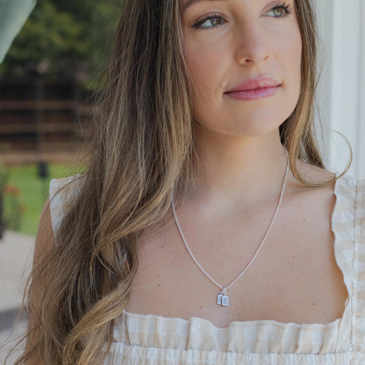 Woman wearing a garment of grace sterlingsilver necklace with a pendant outdoors