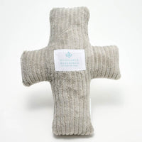 A plush, gray weighted pillow in the shape of a cross with a label that reads 'Huggable Blessings'.