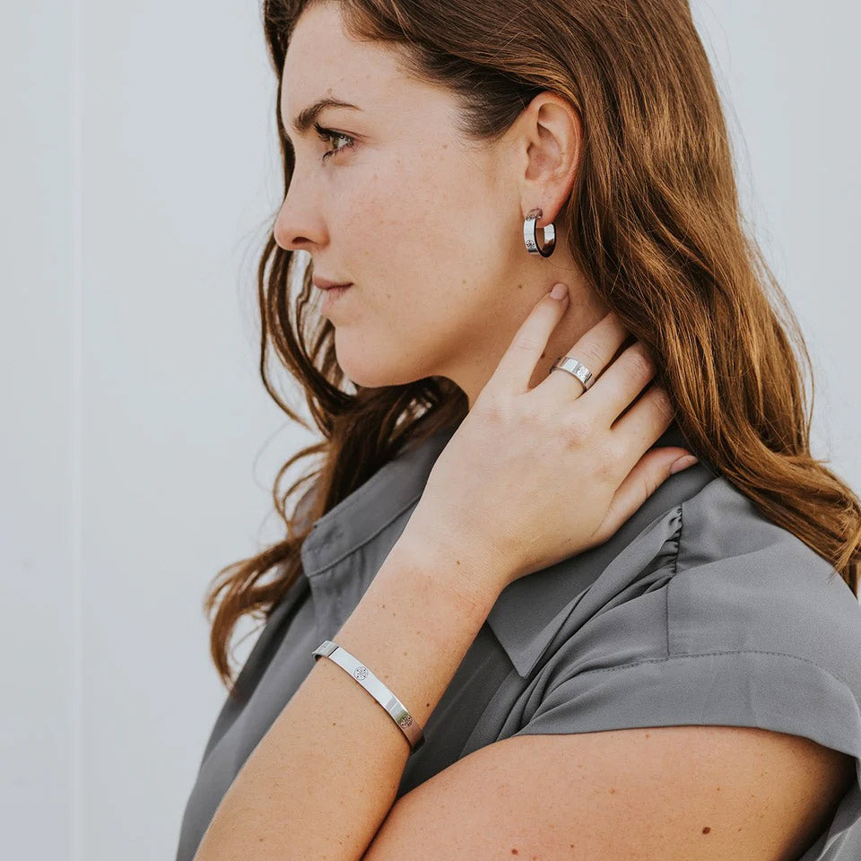 Young brunette woman wearing The Greatest Love Deuteronomy earrings, ring, bracelet bangle in silver