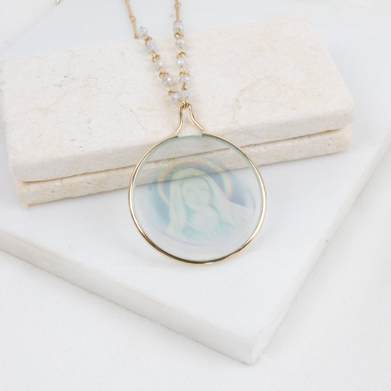 Necklace with a halogram  Mother Mary pendant on a white surface