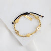 Held by Mary Gold Beads and Miraculous Mary Medal bracelet on black woven cording