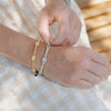 Held by Mary gold and silver tone beaded and Miraculous Mary Bracelets close up on a wrist