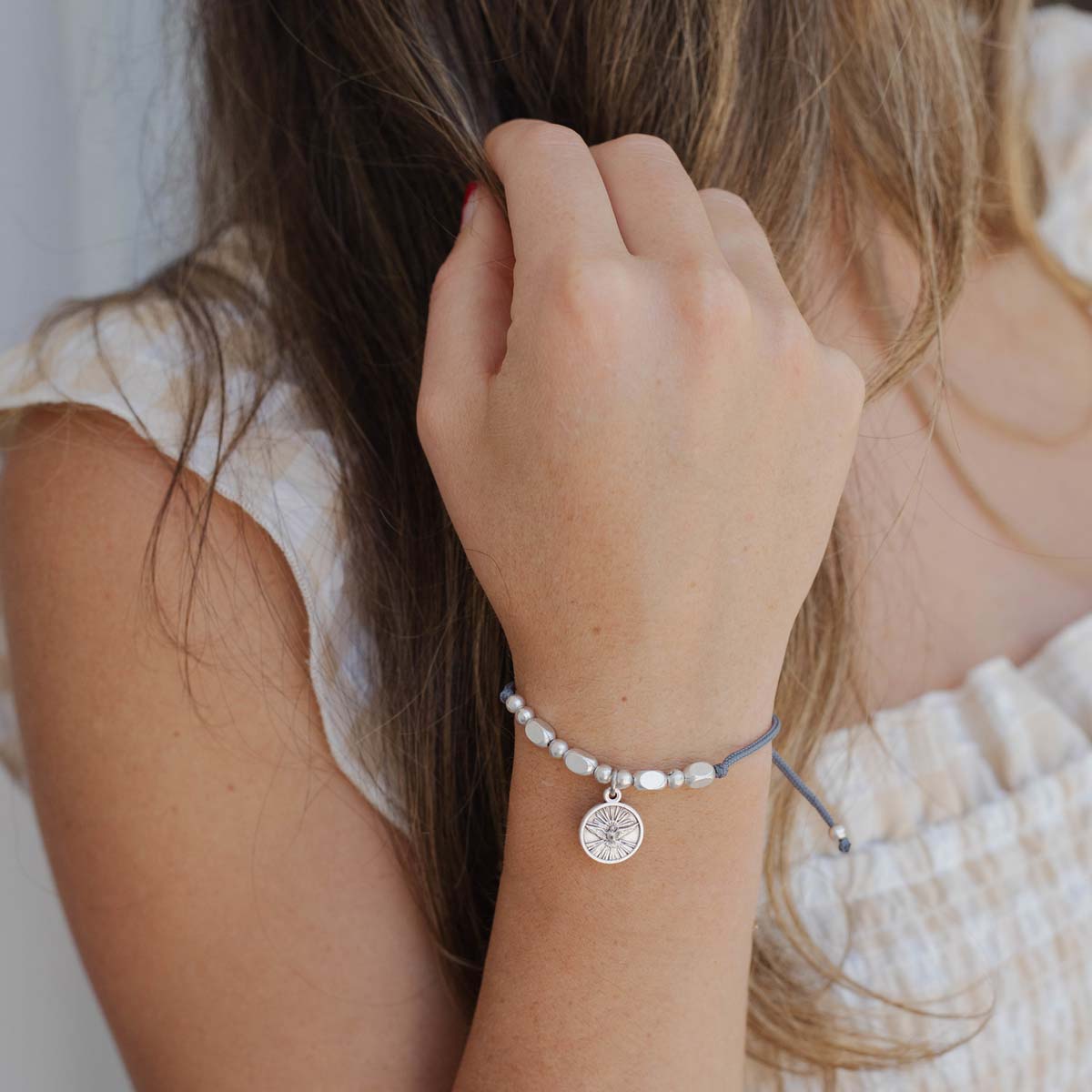 Close-up of a person wearing a bracelet with a Holy Spirit Saint Charm charm on a neutral background
