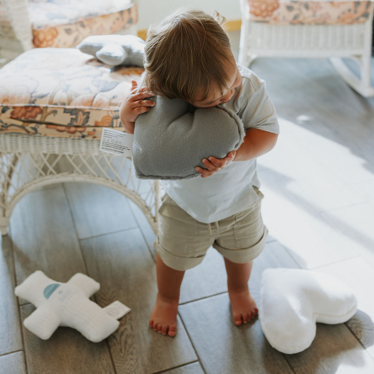 Child holding a gray heart shaped Huggable Prayer  Pillow 