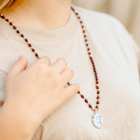 woman wearing a silver tone Joan of Arc hand-beaded gemstone necklace
