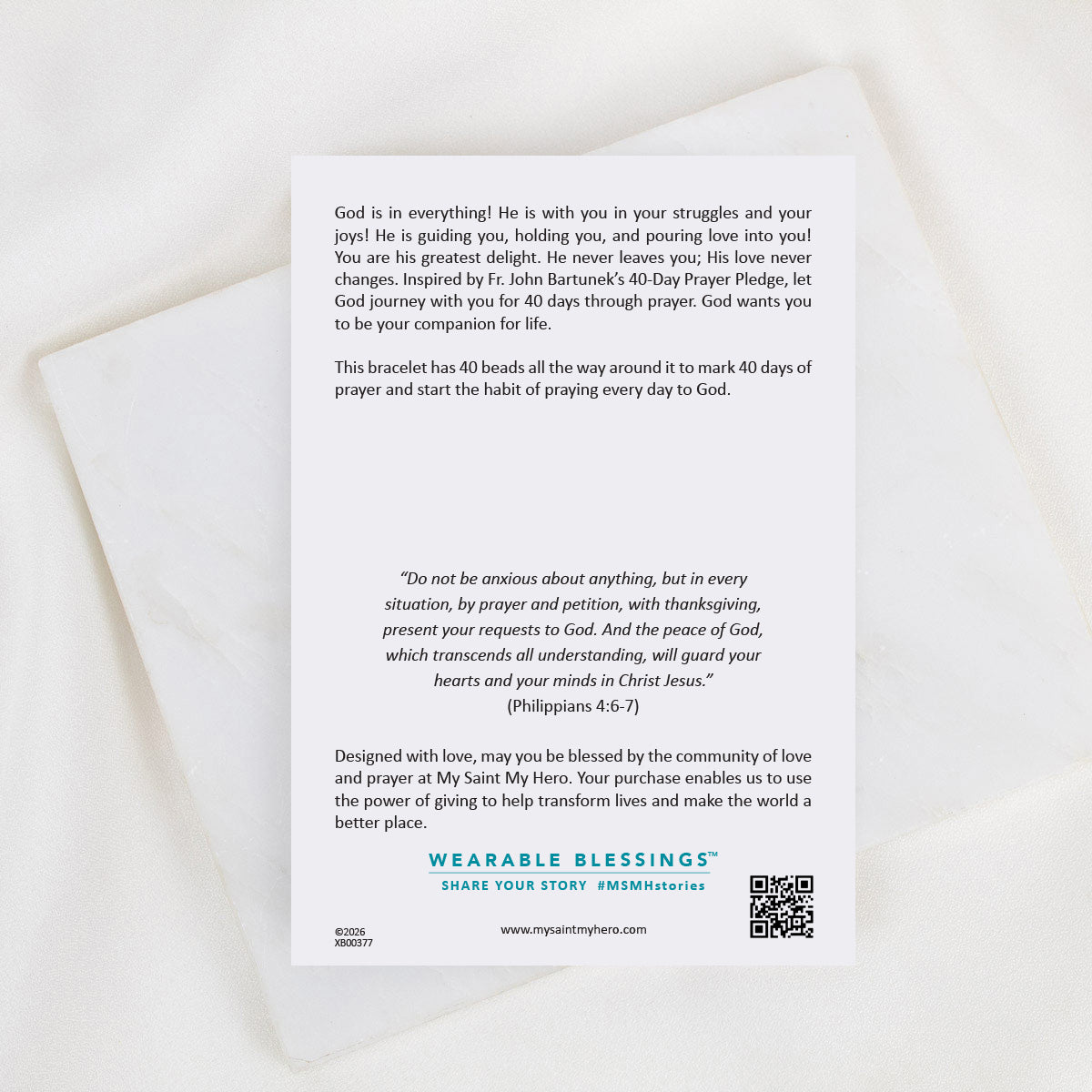 A white rectangular card with printed prayer text and branding for Wearable Blessings, placed on a light marble surface.