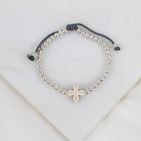 A beaded slipknot bracelet featuring a central textured howlite cross silver-toned beads, a dark gray adjustable cord.