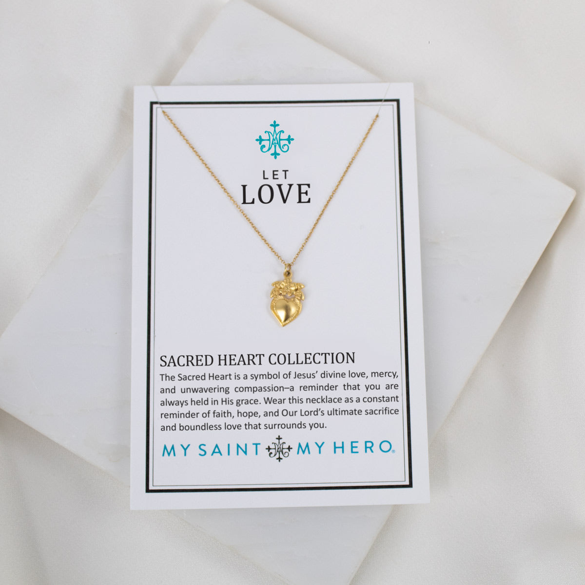 Gold necklace with a heart pendant on a card with text and branding