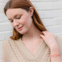 Woman wearing a silver chain and petite mother of pearl heart necklace