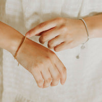 Close up of woman's hands wearing a gold and a silver consecration bracelet