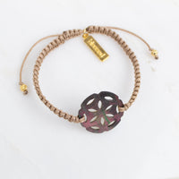 Bracelet with a decorative flower-shaped charm on a white background