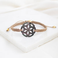 Bracelet with a decorative black flower-shaped clasp on a white background
