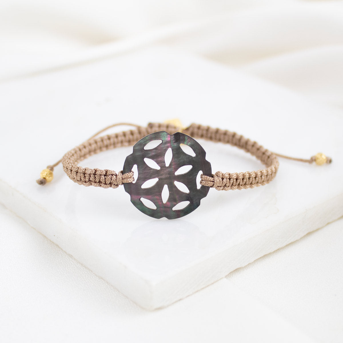 Bracelet with a decorative black flower-shaped clasp on a white background