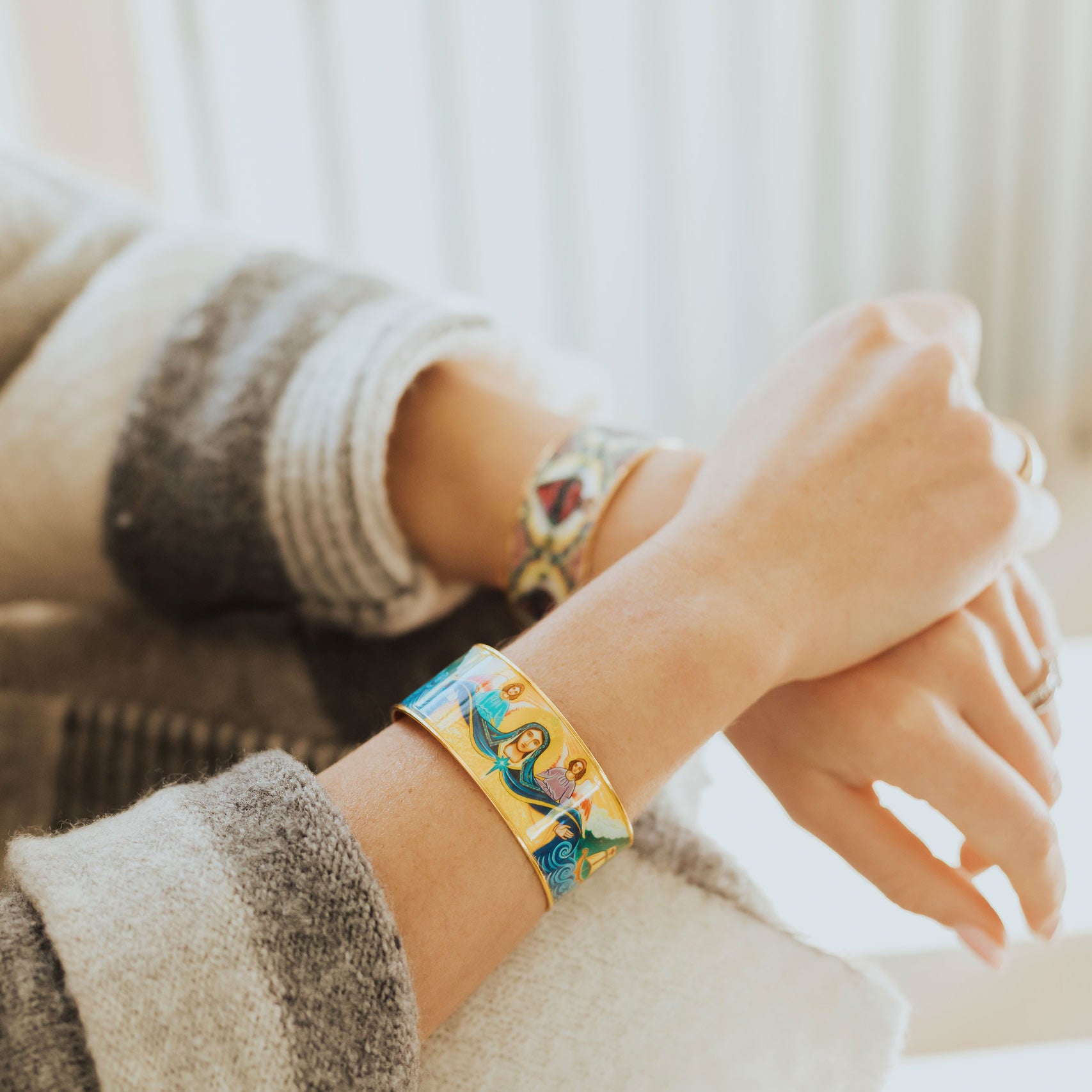 Woman wearing the My Saint My Hero Mary Star of the Sea gold-tone cuff bracelet with a colorful sacred Marian icon.