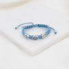 Blue braided bracelet with silver beads on a white surface