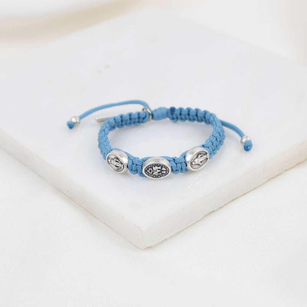 Blue braided bracelet with silver beads on a white surface