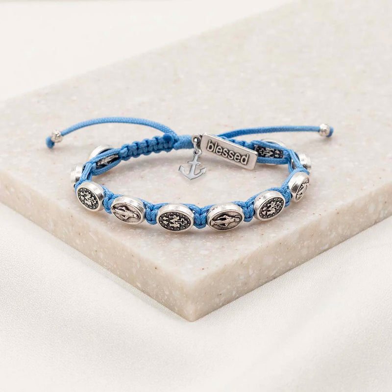 Trust the Journey Miraculous Blessing Bracelet blue woven bracelet with Mary medals a silver anchor charm and a blessed charm tag