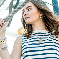Woman wearing a striped shirt and jewelry, holding a rope.
