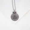 Silver necklace with a decorative Auspice Maria design pendant on a white background