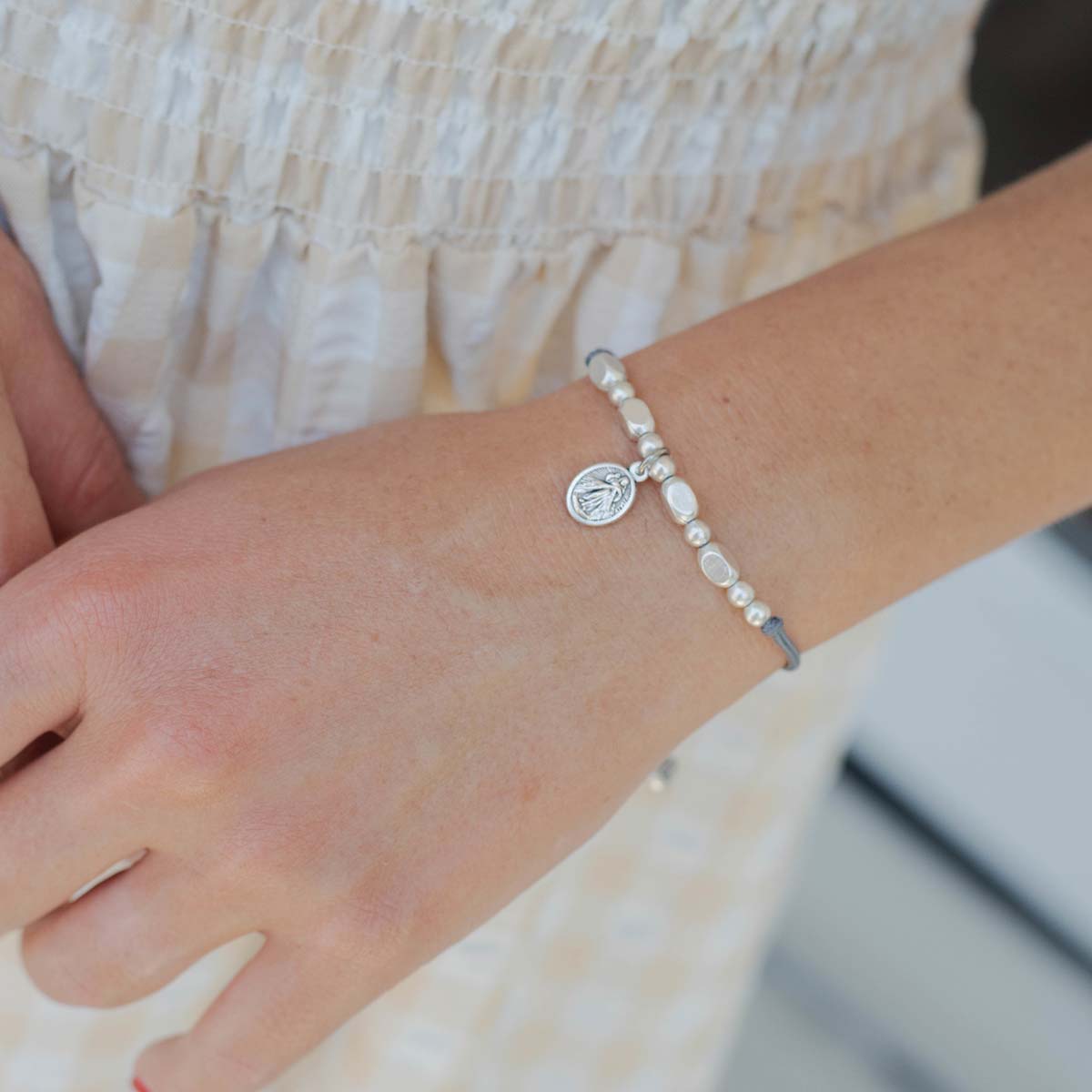 Close-up of a wrist wearing a beaded bracelet with a small charm.