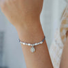Close-up of a wrist wearing a bracelet with beads and a small round charm.