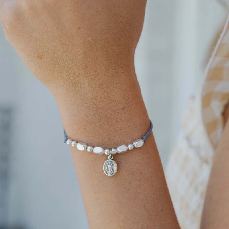 Close-up of a wrist wearing a bracelet with beads and a small round charm.