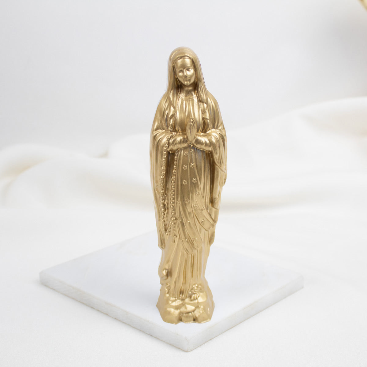 Gold statue of a Our Lady of Lourdes   religious figure on a white base