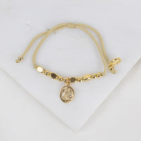 Gold bracelet with a Our Lady of Lourdes medal charm on a white background