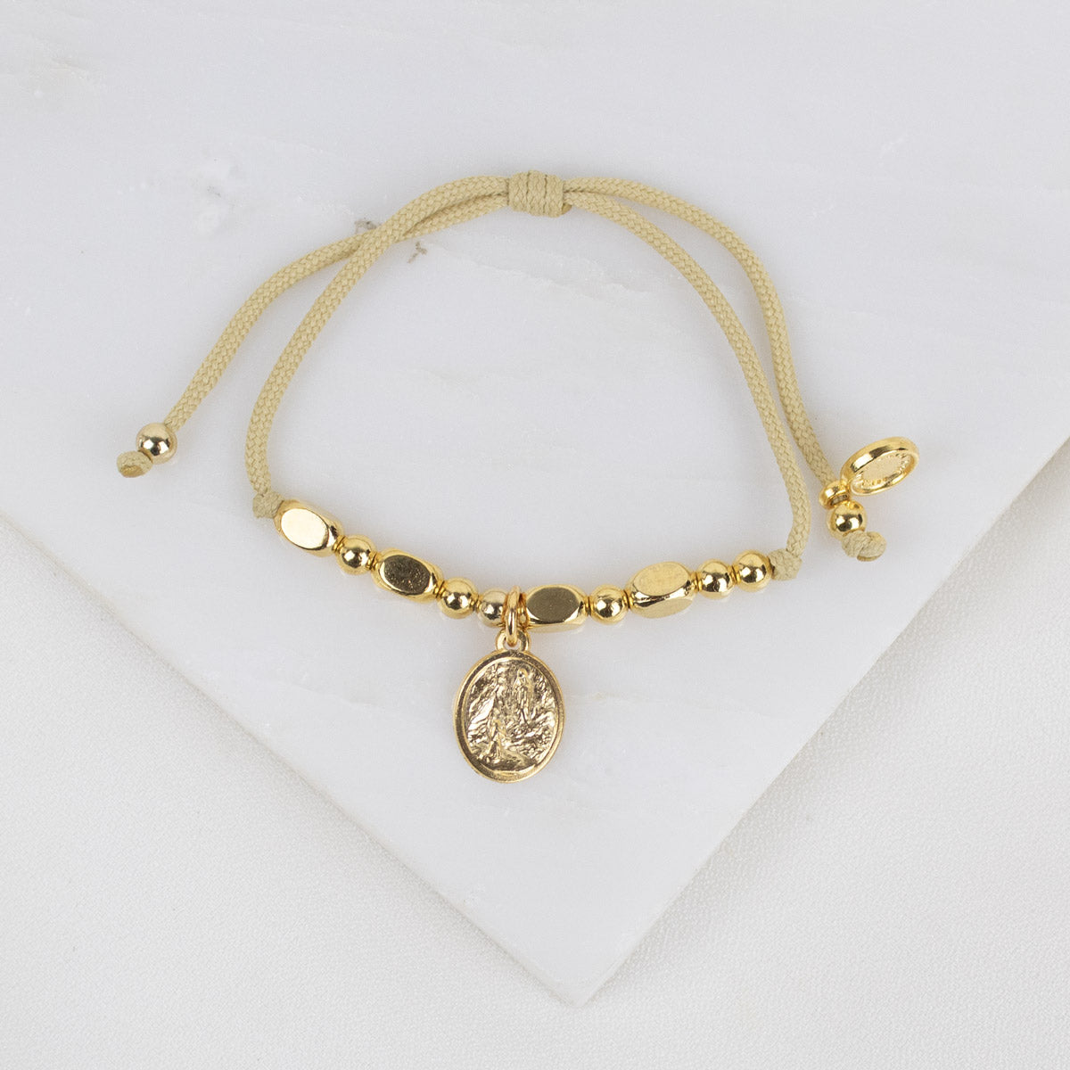 Gold bracelet with a Our Lady of Lourdes medal charm on a white background