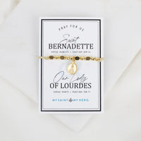 Gold St. Bernadette/Our Lady of Lourdes beaded bracelet with saint charm pendant on a card