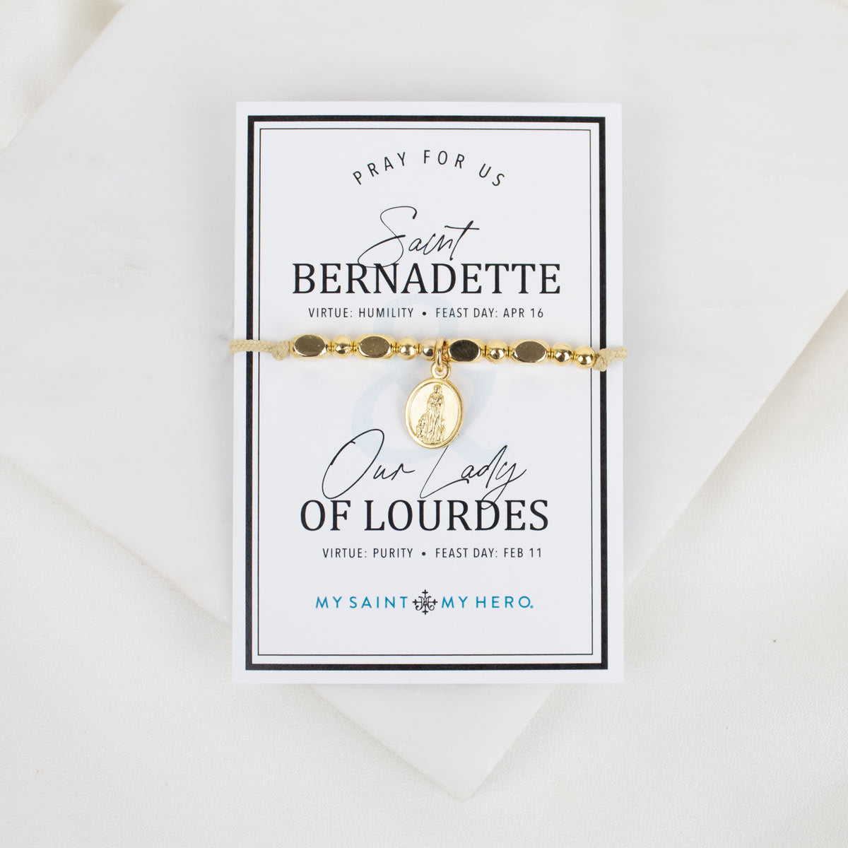 Gold St. Bernadette/Our Lady of Lourdes beaded bracelet with saint charm pendant on a card