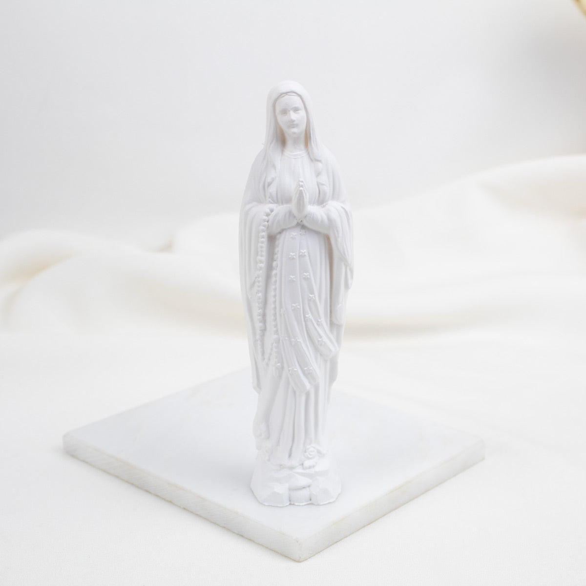 White Our Lady of Lourdes statue of a religious figure on a white platform