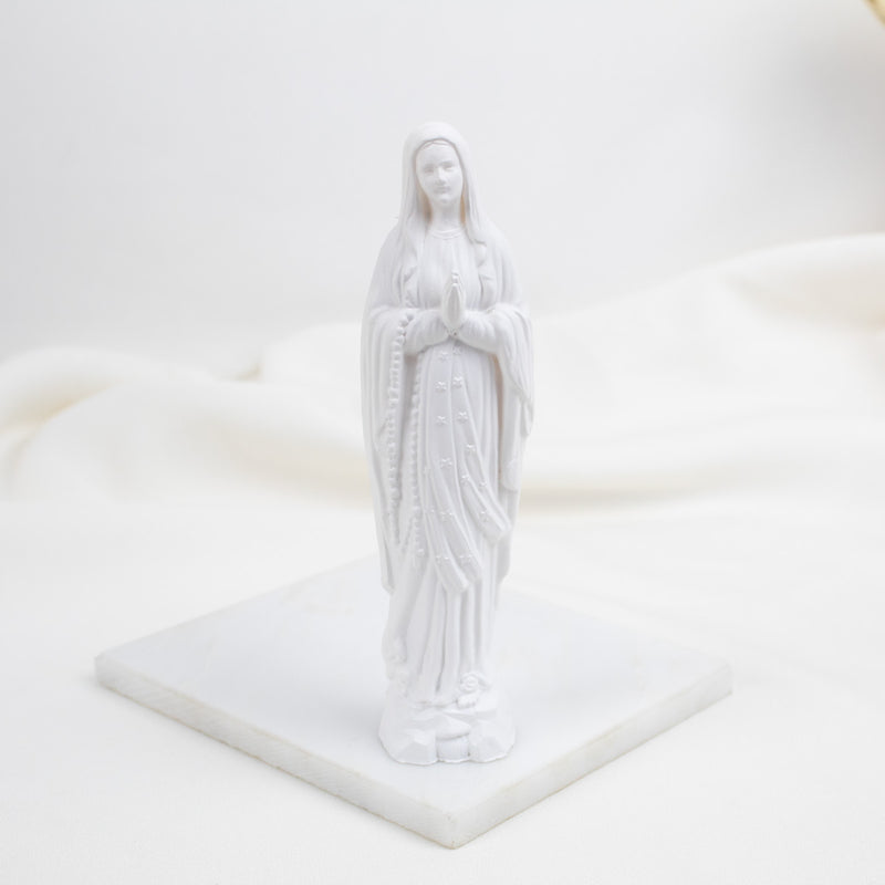 White Our Lady of Lourdes statue of a religious figure on a white platform
