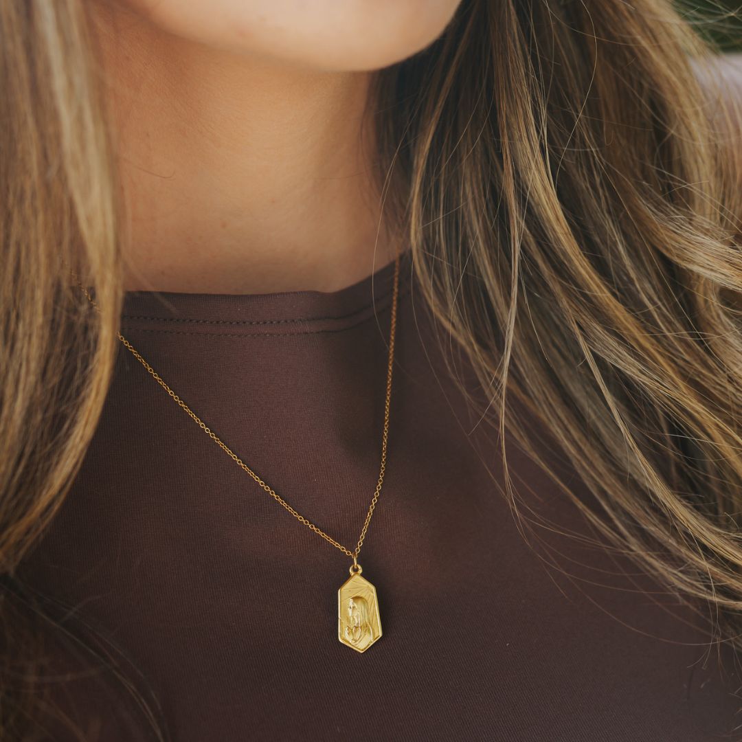 close up of a woman wearing a 14k gold our lady of fatima pendant necklace on a petite chain