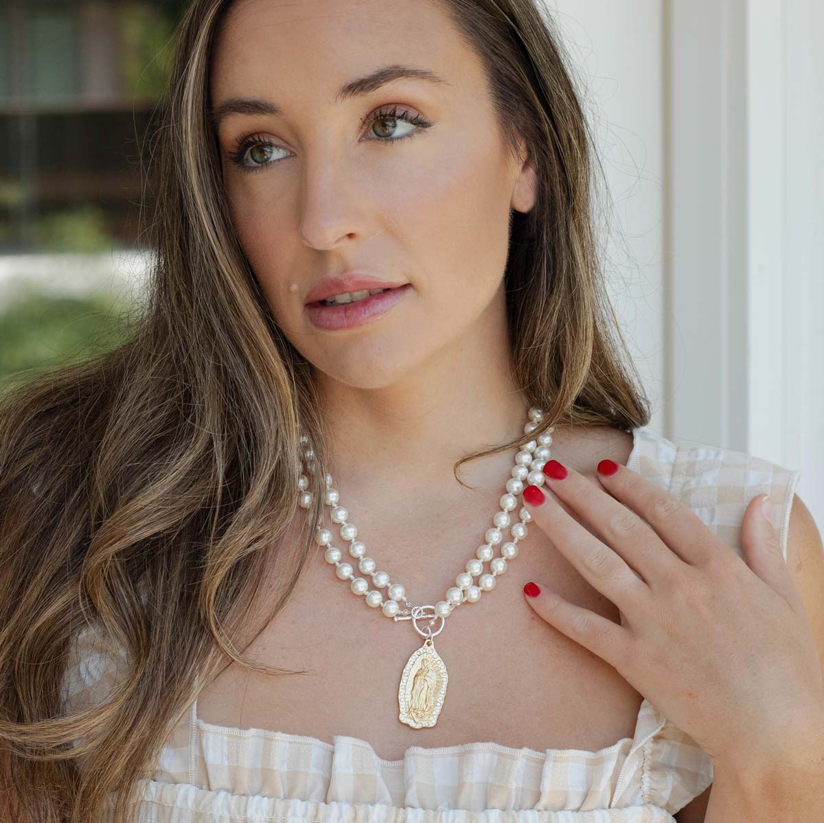Woman wearing a pearl necklace with a pendant indoors