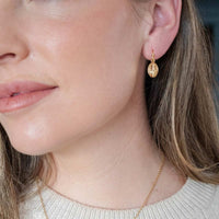 Close-up of a person wearing gold earrings and a necklace.