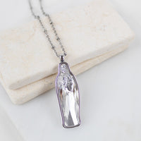Silver chain with a clear crystal Mary pendant necklace on a light background
