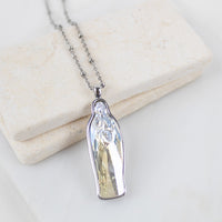 Silver chain with a clear  slightly yellow crystal Mary pendant necklace on a light background