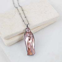 Silver chain with a pink crystal Mary pendant necklace on a light background