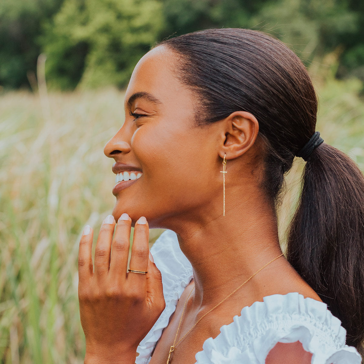 Ribbons of Faith Earrings gold tone on a woman in a white top in a field