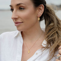 LIfestyle image of young woman wearing gold Let Love Sacred Heart  with Flowers earrings and necklace